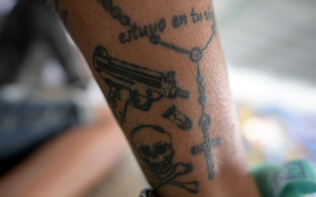 A former combatant of the right-wing paramilitary group United Self-Defence Forces of Colombia (AUC) shows his tattoos during the first National Meeting of AUC ex-combatants, an initiative to construct total peace with the current government, in Puerto Boyaca, Boyaca department, Colombia, on May 6, 2023. (Photo by Raul ARBOLEDA / AFP)
