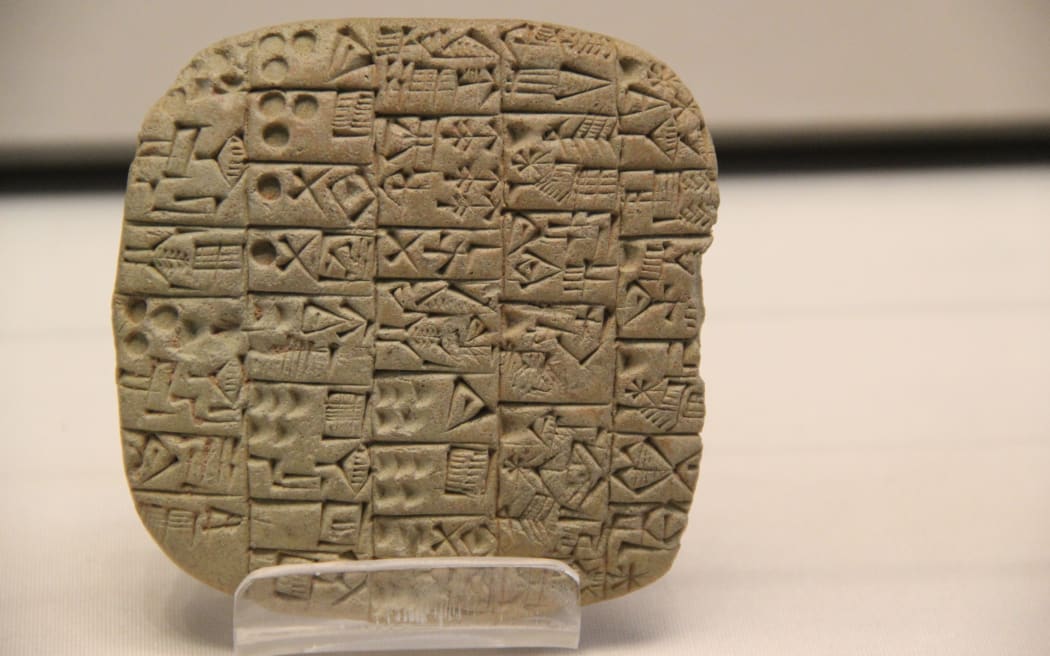 A close-up macro shot of a sumerican cuneiform clay tablet displayed at a museum.