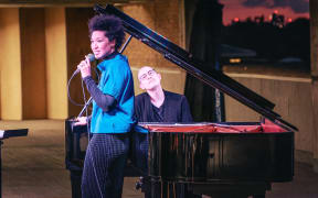 An image of Julia Bullock standing at piano.