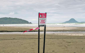 Signs warn beachgoers not to swim on Ōhope Beach in the area surrounding Wharekura Stream.
