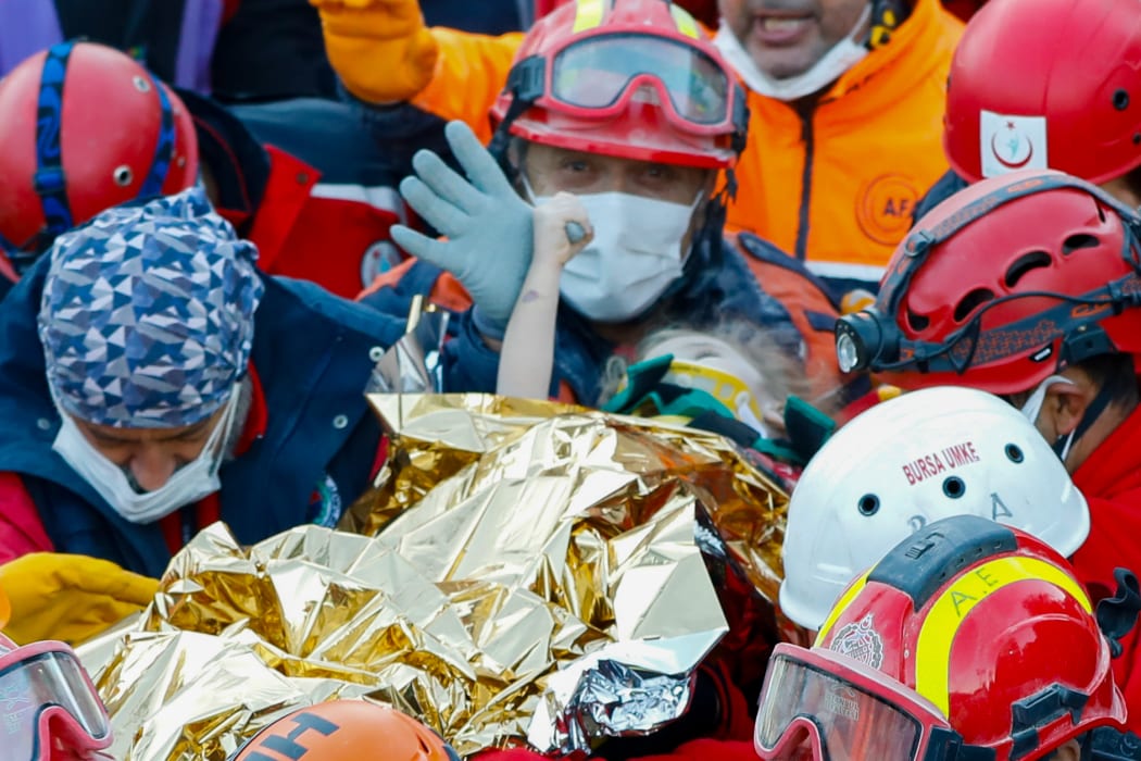 Elif Perincek, a three-year-old survivor, holding the thumb of a rescue worker as she is carried out of a collapsed building after an earthquake in Izmir on 2 November, 2020.