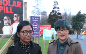 A photo of Saziah Bashir and Fern Seato outside election campaign billboards