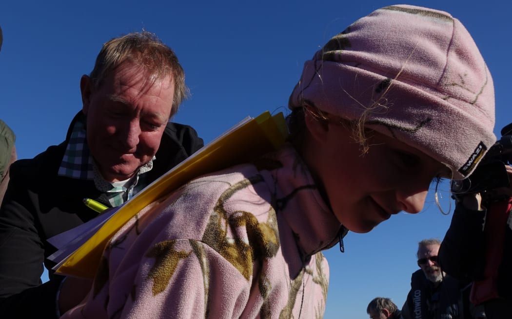 Billy Comer lets Conservation Minister, Nick Smith use her back to sign an agreement with the Hollyford Conservation Trust.
