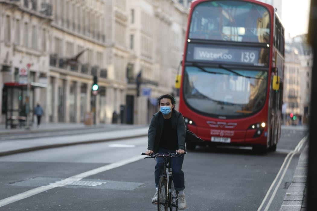 A man wearing a face mask as a preventive measure against the coronavirus (Covid-19) pandemic rides his bike in central London, England on May 5, 2020.