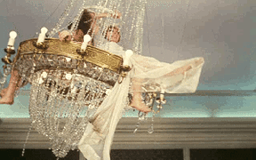 a gif of two people swinging on a chandelier