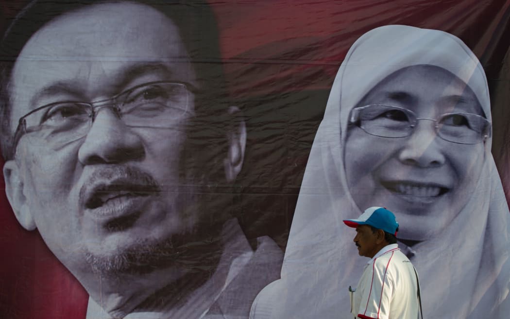 A supporter walks past a banner of Malaysian opposition leader Anwar Ibrahim (left) and his wife Wan Azizah at the Federal Court on 10 February.
