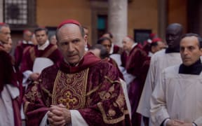 Ralph Fiennes as a Cardinal with other Cardinals looking on.