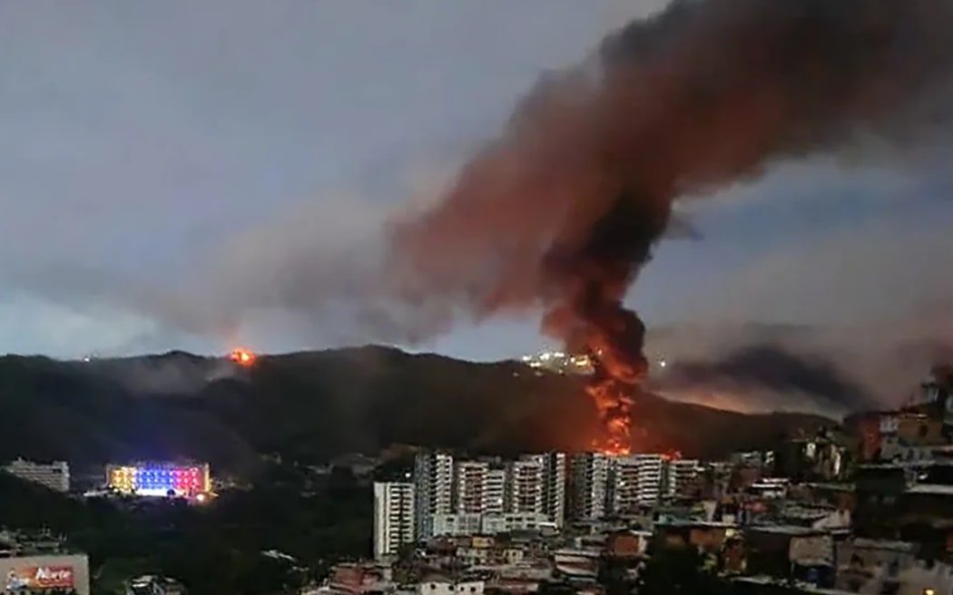Fire at Fuerte Tiuna, Venezuela's largest military complex, is seen from a distance after a series of explosions in Caracas on January 3, 2026. The United States military was behind a series of strikes against the Venezuelan capital Caracas on Saturday.