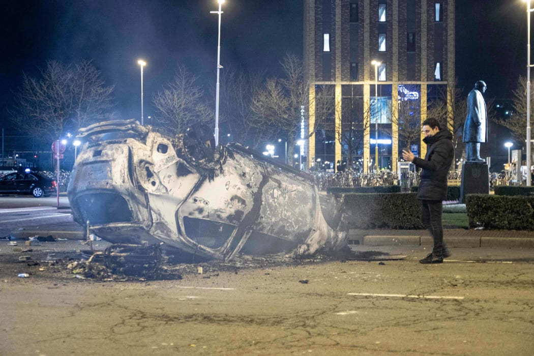 A burned car in front of Eindhoven central train station after the anti-lockdown protest.