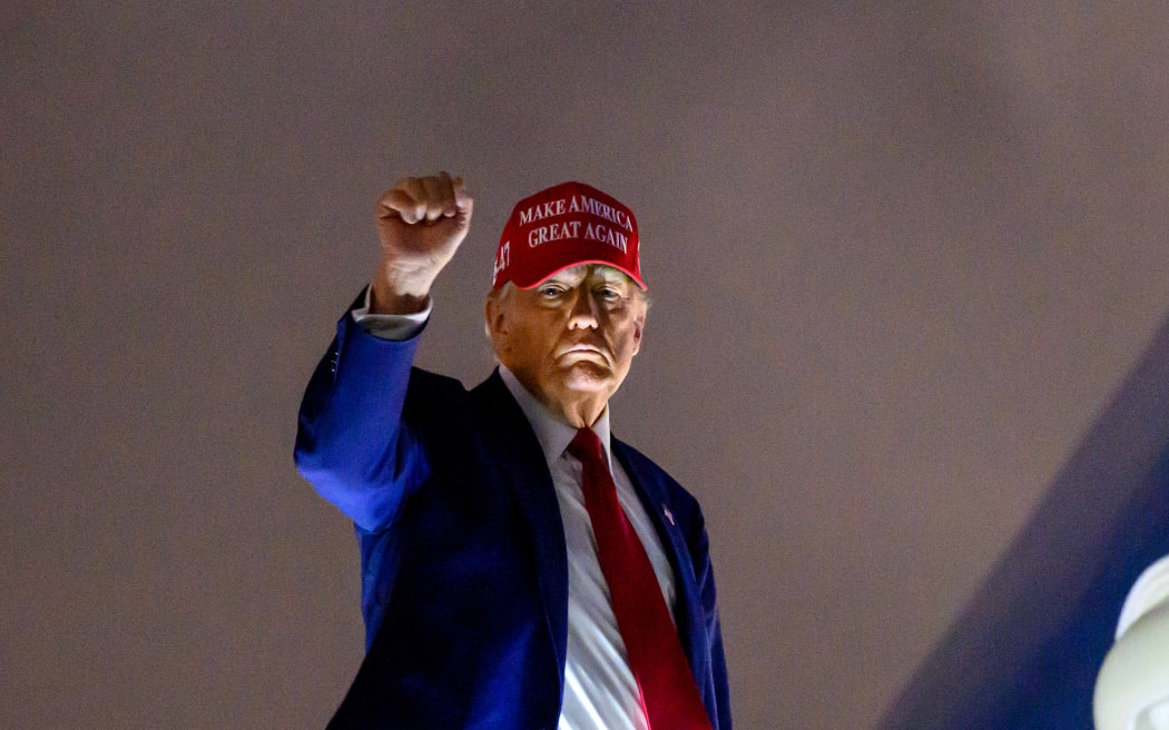 US President Donald Trump pumps his fist as he boards Air Force One before departing Miami International Airport, in Miami, Florida on April 3, 2025. Trump is travelling to his Mar-a-Lago Resort. (Photo by Mandel NGAN / AFP)