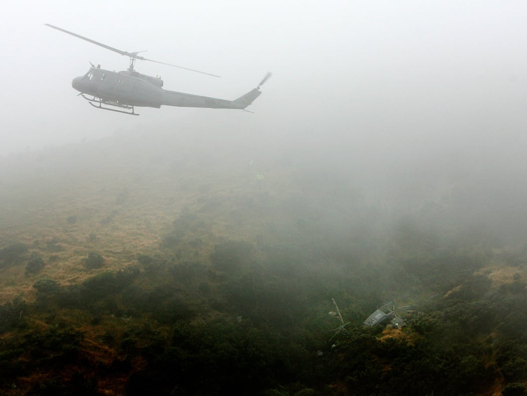 An Air Force Iroquois hovers above the crash site.