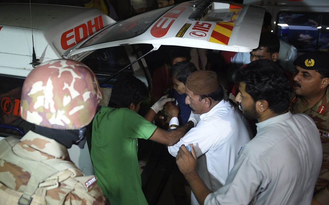 Volunteers move an injured blast victim from an ambulance at a hospital in the Hub district, some 40 kilometers from Karachi, Pakistan.