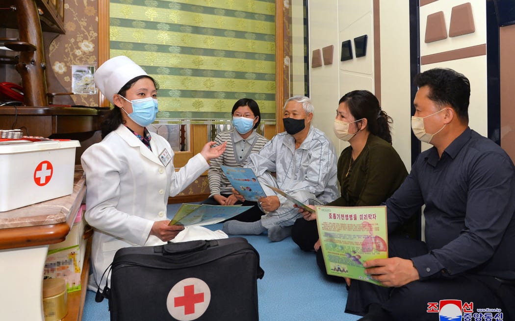 This picture taken on 17 May 2022 and released from North Korea's official Korean Central News Agency (KCNA) on 18 May shows a doctor promoting epidemic prevention measures to prevent the spread of the Covid-19 coronavirus in Pyongyang.