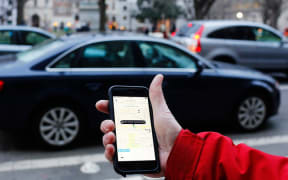 A mans hand holding a smartphone with the Uber app running