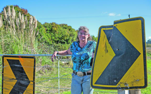 Tracy Watson has retrieved battered chevron signs from the paddock she leases and tied them to her gate to help warn people travelling fast as they exit the bridge.