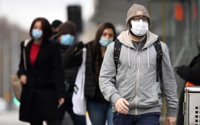 Commuters walk past Melbourne's Flinders Street Station on July 23, 2020 on the first day of the mandatory wearing of face masks in public areas as the city experiences an outbreak of the COVID-19 coronavirus.