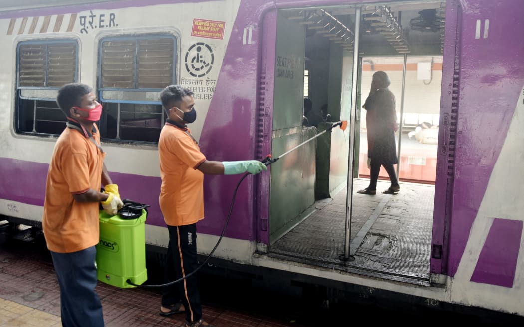 Railway worker sanitises a suburban train compartment / carriage amid Coronavirus emergency in Kolkata, India, 15 June, 2021.