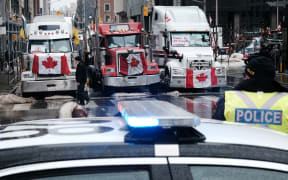 People walk near Canadian Parliament buildings as hundreds of truck drivers and their supporters gather to block the streets of downtown Ottawa as part of a convoy of truck protesters against Covid mandates.
