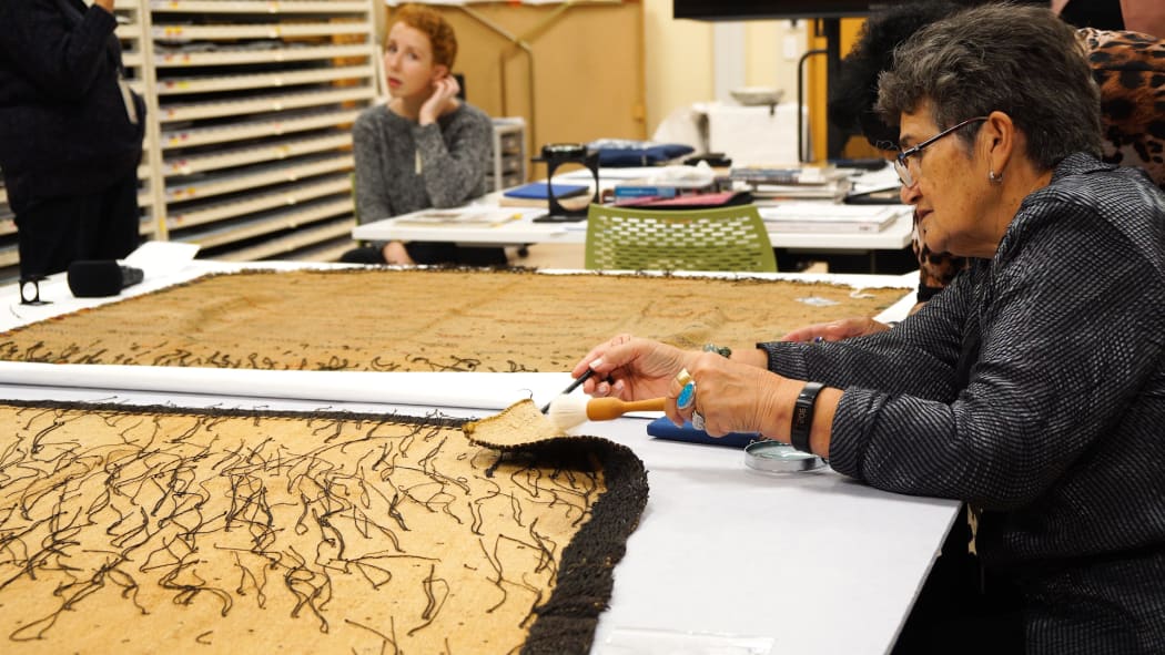 Christina Wirihana looking at the back of a korowai (cloak).