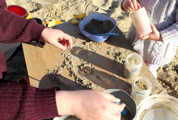 A close up of a mother with her child playing in the sandpit