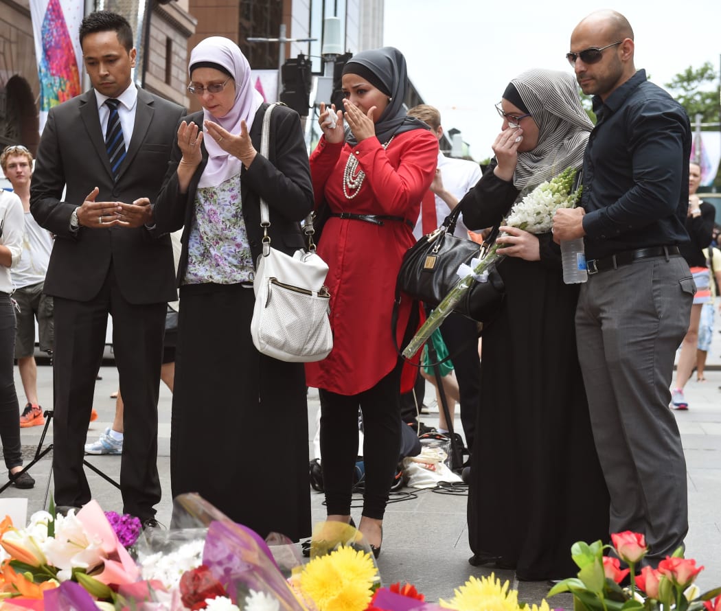 Representatives of the Muslim community pray after laying flowers at a floral memorial at the scene of the Sydney siege.