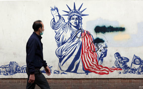 A man walks past a mural depicting the US Statue of Liberty with the torch-bearing arm broken, painted on the outer walls of the former US embassy, in Tehran on February 6, 2026. Iran and the United States began talks in Oman on February 6, with Washington refusing to rule out military action against the Islamic republic over its deadly crackdown on mass protests. (Photo by AFP)
