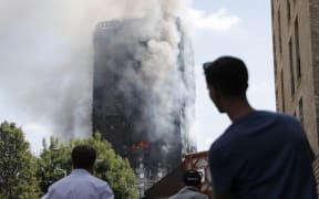 People look up towards Grenfell Tower as daylight revealed the 24-storey block still burning.