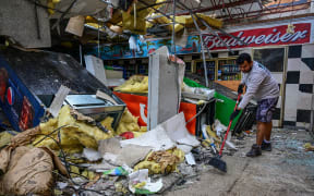 A man cleans debris inside a gas station store in Lakewood Park, Florida, after a tornado hit the area and caused severe damage as Hurricane Milton swept through Florida on October 10, 2024. - At least 10 people were dead after Hurricane Milton smashed into Florida, US authorities said, after the monster weather system sent tornados spinning across the state and flooded swaths of the Tampa Bay area. (Photo by GIORGIO VIERA / AFP)