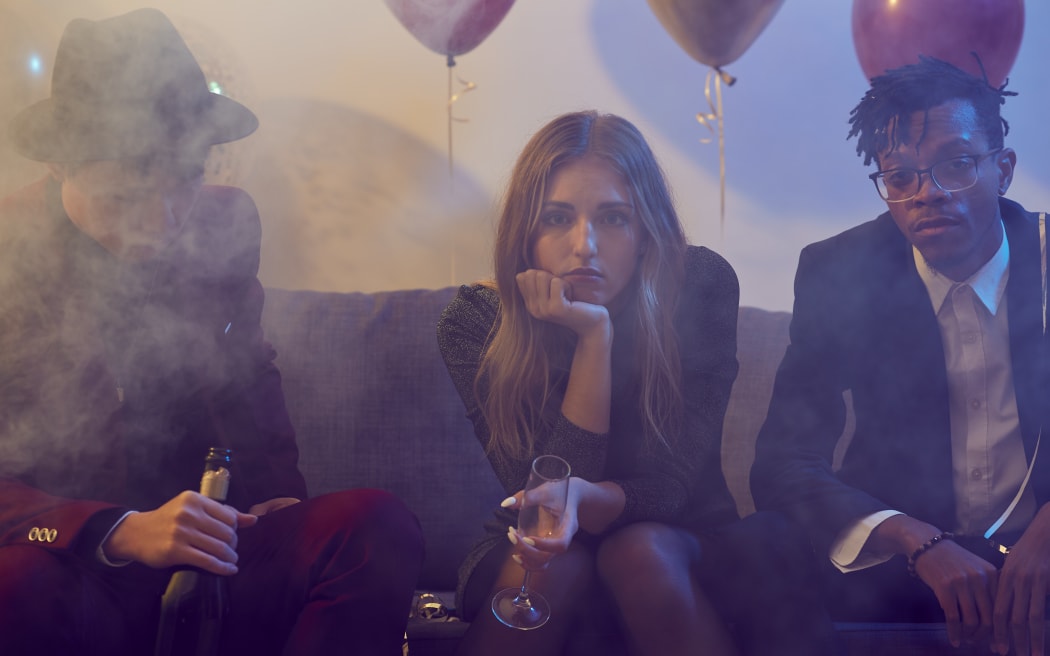 Young woman holding champagne glass while siting on sofa during party in a nightclub.