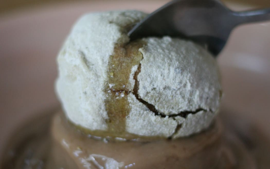 A deep fried feijoa rolled in feijoa skin sherbet. It is sitting on a bed or toffee couloured icecream.