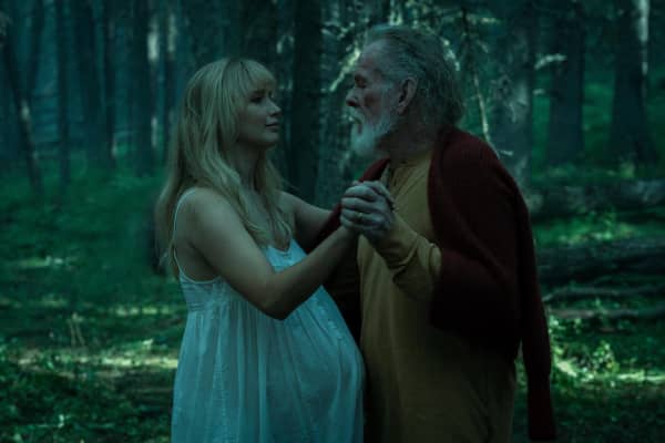 Jennifer Lawrence, wearing a white nightgown, dances with Nick Nolte in a shady forest.