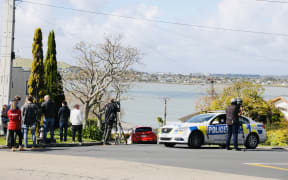 Police and onlookers at Hillsborough, Auckland, after a person in possession of a firearm was shot by police and is in a serious condition following a chase that ended on Lilac Grove.