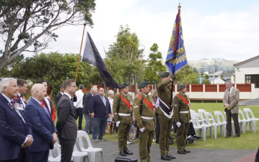 Army members hold flags as the Minister for Veterans, Chris Penk, and other guests mark 80 years since the return from WW2 of the surviving members of Māori Battalion at Takapūwāhia Marae where Nati Toa welcomed iwi members in 1946.