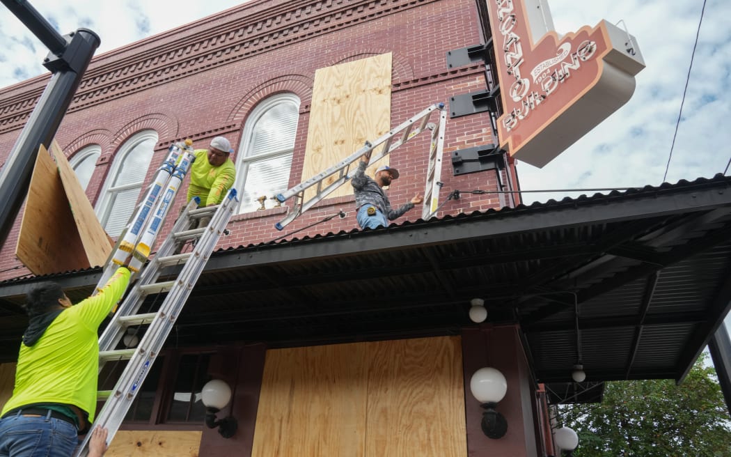 Contractors put plywood over windows at the El Encanto Building in the Ybor City section of Tampa ahead of Hurricane Milton’s expected landfall in the middle of this week on October 8, 2024 in Florida. - Hurricane Milton exploded in strength October 7 to become a potentially catastrophic Category 5 storm bound for Florida, threatening the US state with a second ferocious hurricane in as many weeks.