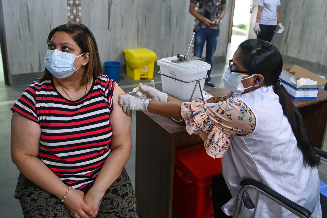 A health worker inoculates a woman with a dose of the Covishield Covid-19 coronavirus vaccine at a vaccination centre in New Delhi on May 13, 2021.