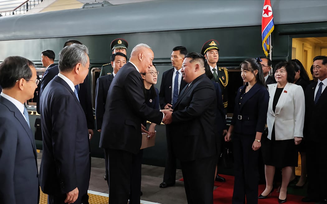 North Korea's leader Kim Jong Un (centre R) and his daughter Kim Ju Ae (3rd R) being greeted by Chinese officials upon their arrival at the Beijing Railway Station.