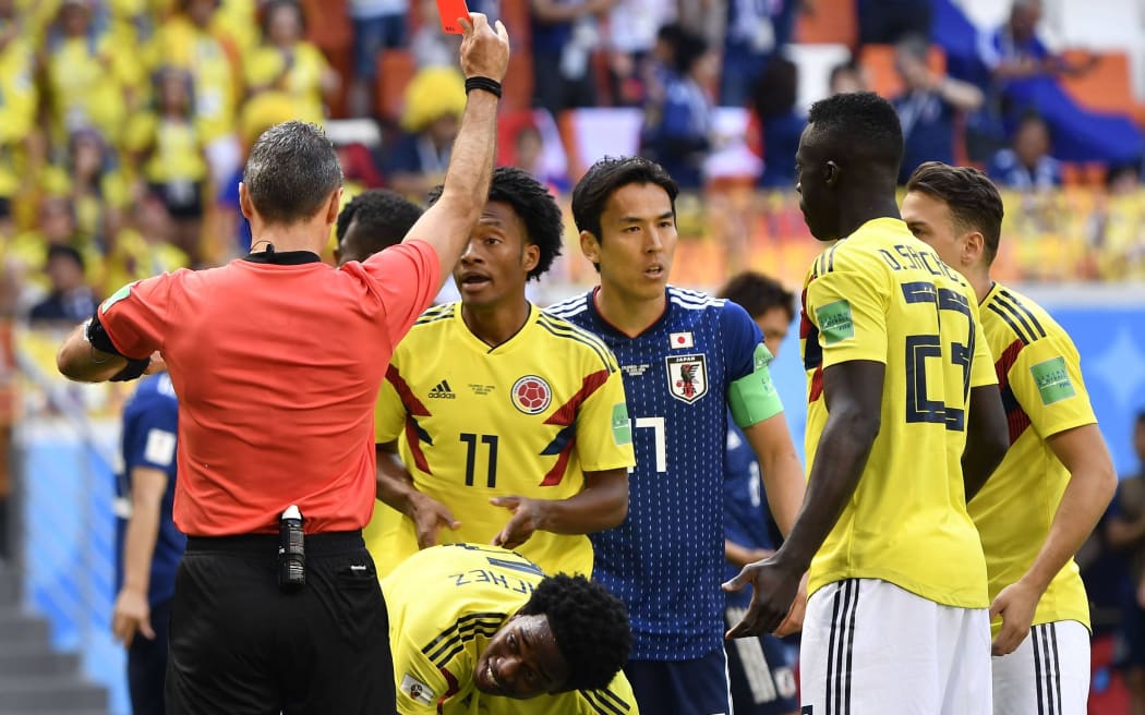 Colombian players argue a red card for defender Carlos Sanchez after he clearly and deliberately handled the ball and gave away a penalty against Japan.