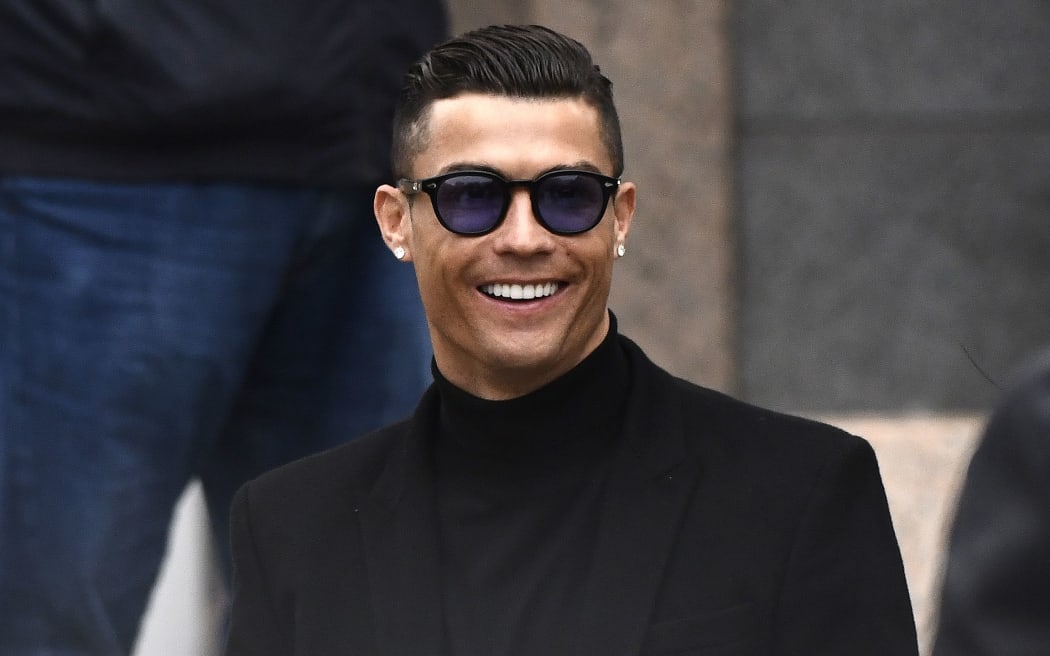 Cristiano Ronaldo smiles as he leaves after attending a court hearing for tax evasion in Madrid