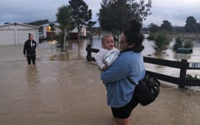 Isabella Ngawati evacuates an Ōtiria Rd home with six-month-old Elijah during the 2020 flood while Gwen Ngawati opts to stay behind.