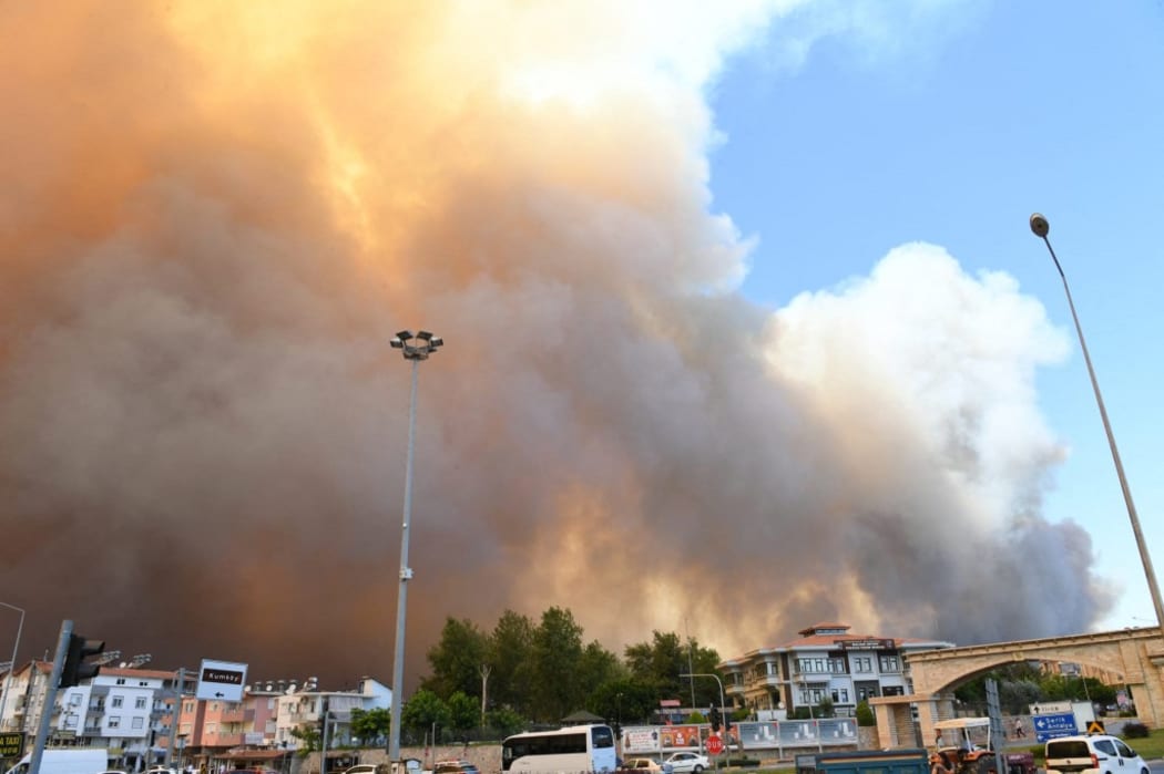 Flames and a massive cloud of smoke cover a fire-hit area in Manavgat, Antalya, southern Turkey, July 28, 2021. At least three people were killed, 100 injured and several have been evacuate in the massive wildfires of the resort city.