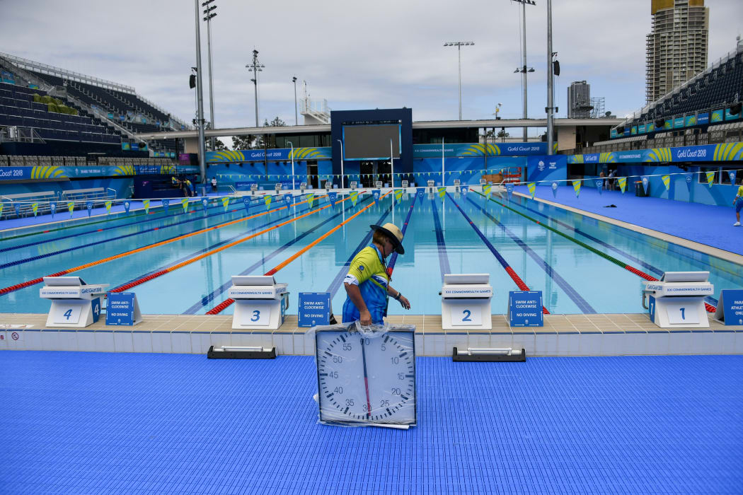 A volunteer carries a timing clock at the Optus Aquatic Centre ahead of the 2018 Gold Coast Commonwealth Games on March 30, 2018. / AFP PHOTO / YE AUNG THU