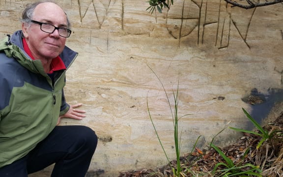 Bruce Hayward next to a cross-section of a moa footprint on a Muriwai road cutting.