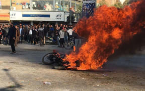 Iranian protesters gather around a burning motorcycle during a demonstration against an increase in gasoline prices in the central city of Isfahan, on November 16, 2019.