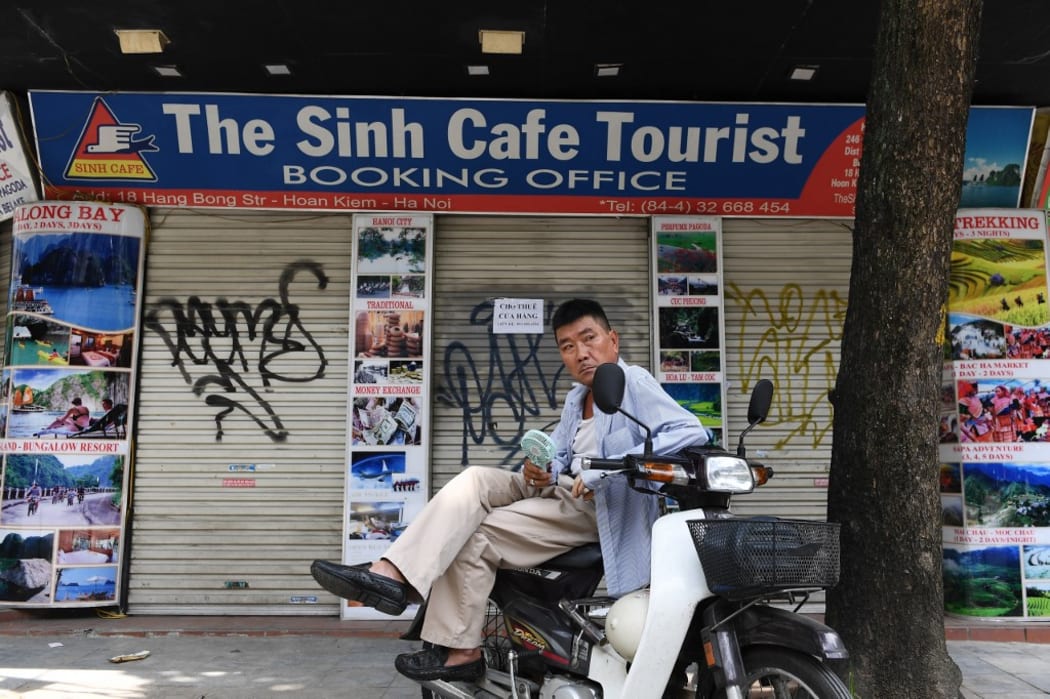 A motorcycle taxi rider waits for customers in front of a tourist office, closed due to the current COVID-19 novel coronavirus situation, in Hanoi.