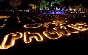 A Thai student places candles on a sand sculpture during commemorations on the the tenth anniversary of the 2004 tsunami at Patong beach in Phuket.