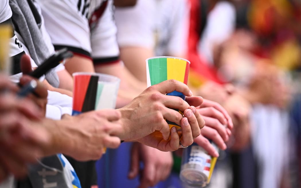 Football fans holding beer cups during a Euro 2024 match.