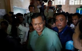 Hun Manet (in green), commander of the Royal Cambodian Army and eldest son of Prime Minister Hun Sen, leaves after casting his vote at a polling station in Phnom Penh on 23 July, 2023.