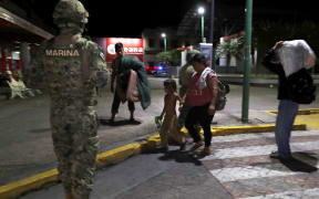 A Mexican marine stands by as camping migrant families are evicted from a park in Tapachula, Mexico, early Wednesday, May 29, 2019.