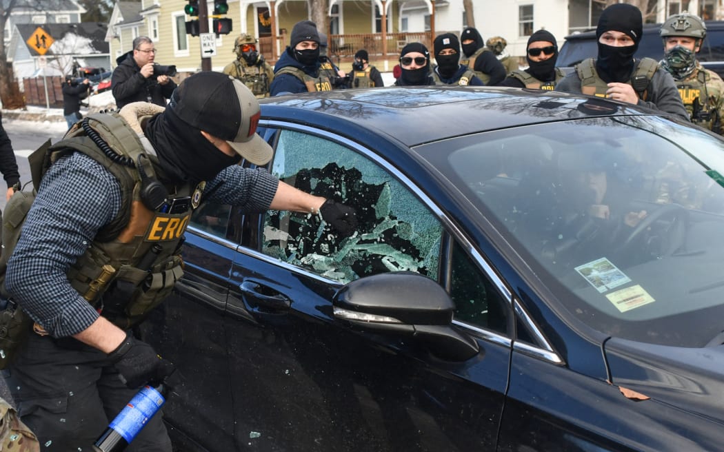 A federal officer breaks a car window as they begin the process of removing a woman from her vehicle near an area where ICE was operating in Minneapolis, Minnesota, on January 13, 2026. Hundreds more federal agents were heading to Minneapolis, the US homeland security chief said on January 11, brushing aside demands by the Midwestern city's Democratic leaders to leave after an immigration officer fatally shot a woman protester. In multiple TV interviews, US Homeland Secretary Kristi Noem defended the actions of the officer who shot and killed 37-year-old Renee Nicole Good, whose death has sparked renewed protests nationwide against President Donald Trump's immigration crackdown. (Photo by Octavio JONES / AFP) / ALTERNATE CROP