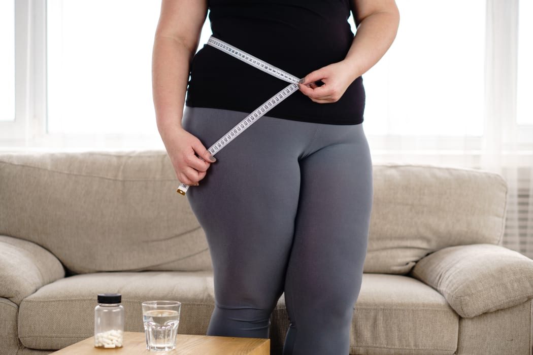 obese woman with pills and measure tape